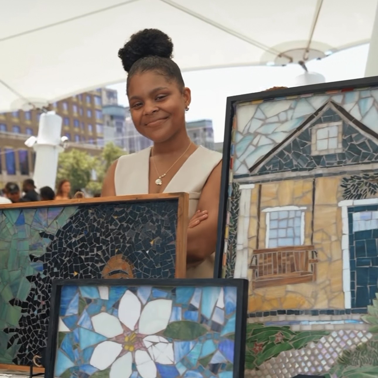 Caitlin Barnes in her New Orleans studio, holding a piece of stained glass to the window light.